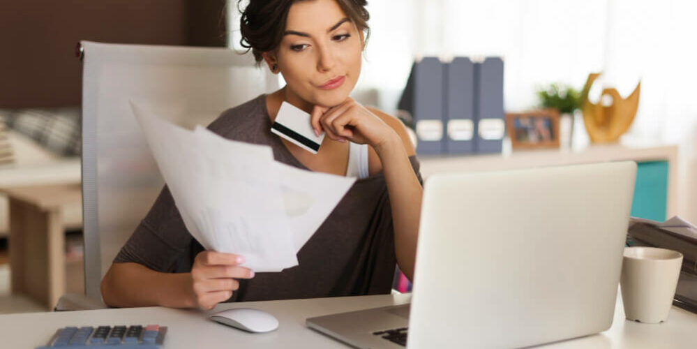 woman looking at laptop and papers