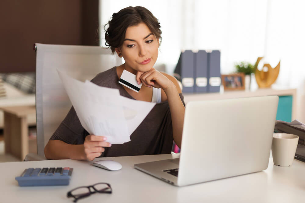 woman looking at laptop and papers