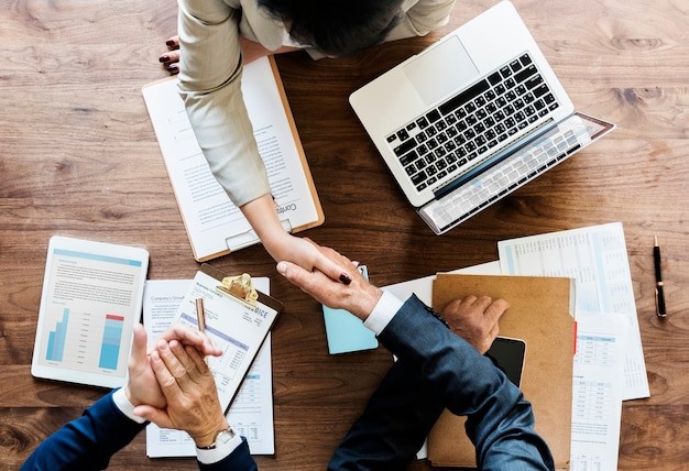 Professional executives shaking hand on table with laptop