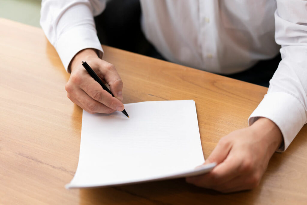 Man about to start a letter with blank page and a pen