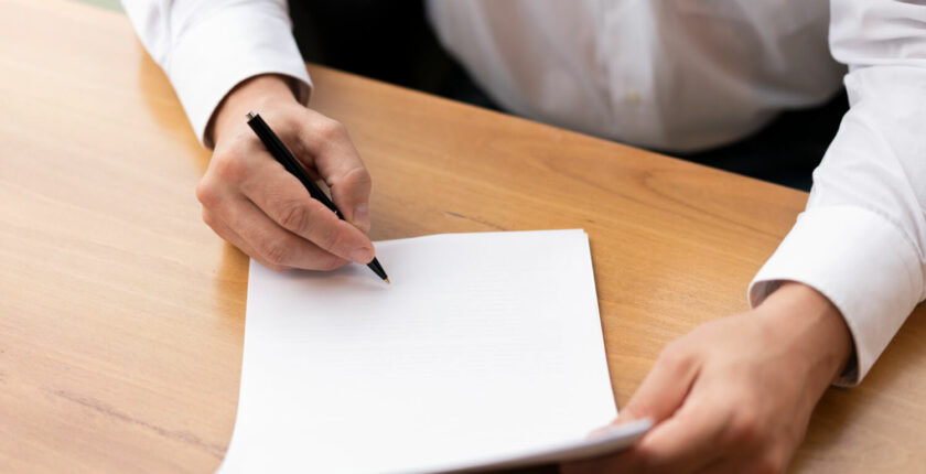 Man about to start a letter with blank page and a pen